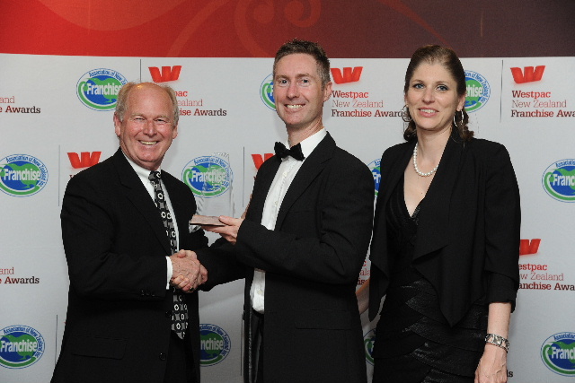 Wayne Billings of sponsors Waipuna Hotel & Conference Centre (left) presents the award to Just Cabins franchisors Fenton and Cindy Peterken. Wayne Billings of sponsors Waipuna Hotel & Conference Centre (left) presents the award to Just Cabins franchisors Fenton and Cindy Peterken.